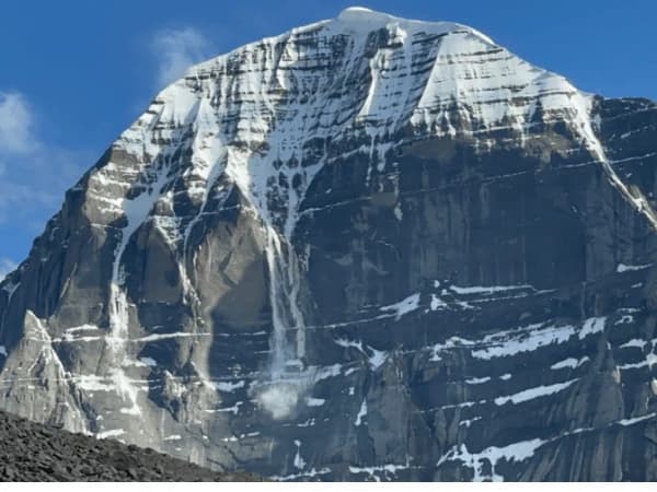 Close-up view of Mount Kailash with snow-covered ridges under a clear blue sky.